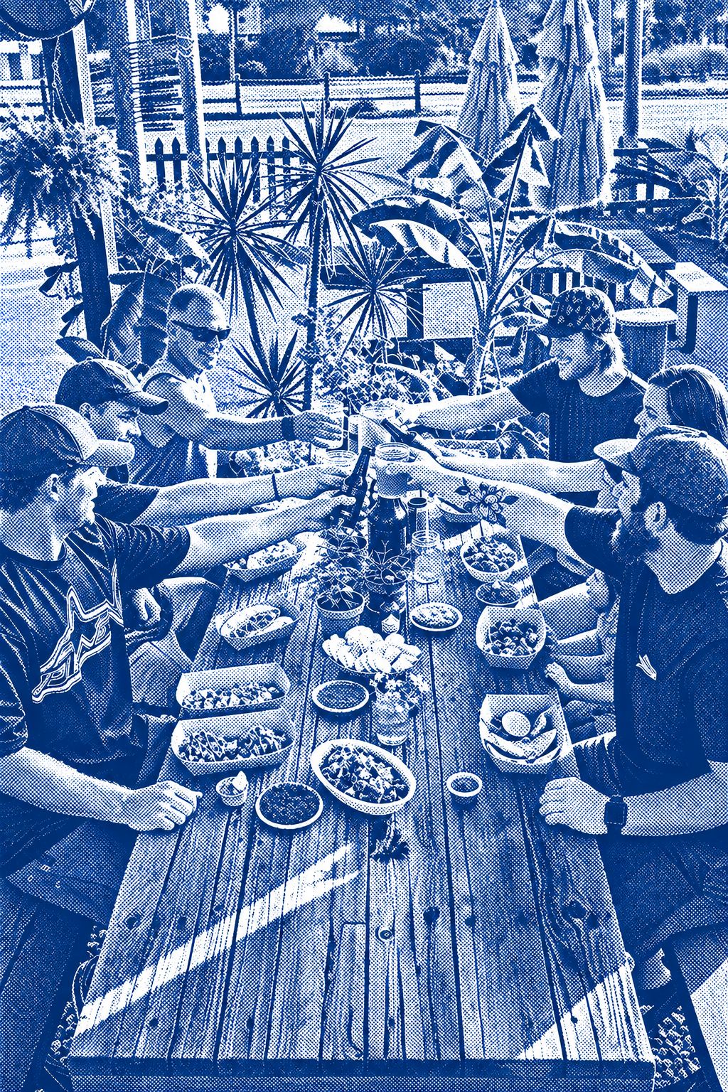 A crew raising drinks over a long patio table full of Finns tacos, burritos and bowls