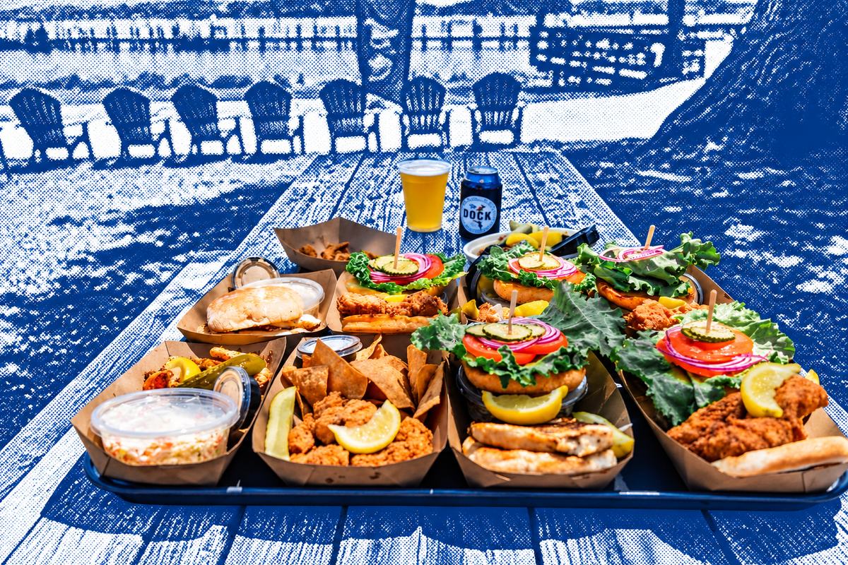 Grouper sandwiches, fried shrimp, chips and slaw on a picnic table at Squared Grouper, with Adirondack chairs and the water behind